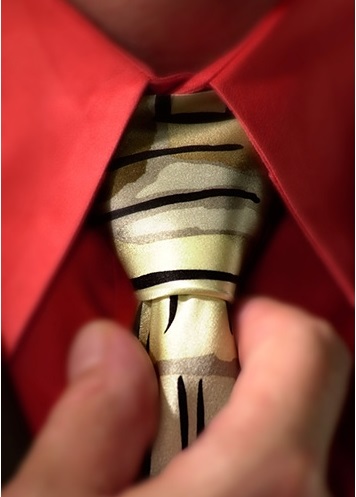 Executive photography of close up of a person adjusting a tie with a red shirt.